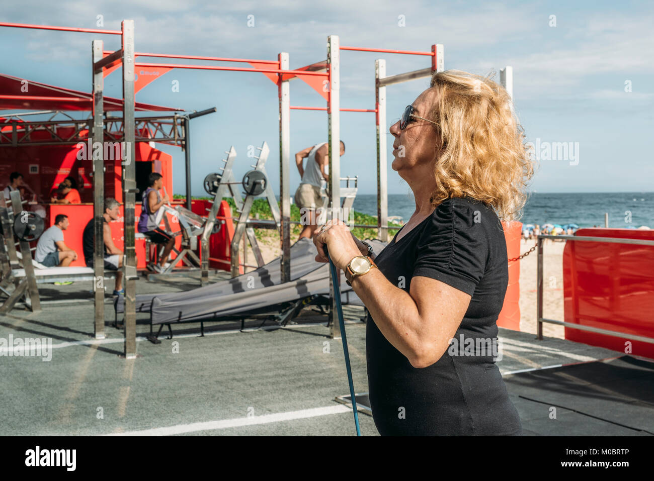 Model Released: Mature woman (70-75) exercising with a stretch cord at open air public gym in Ipanema Beach, Rio de Janeiro, Brazil Stock Photo