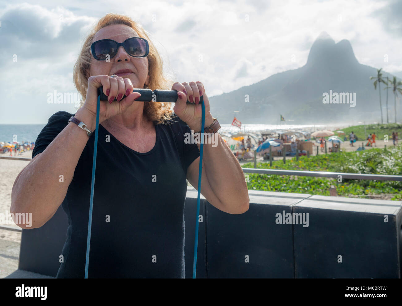 Model Released: Mature woman (70-75) exercising with a stretch cord at open air gym in Ipanema Beach, Rio de Janeiro, Brazil Stock Photo