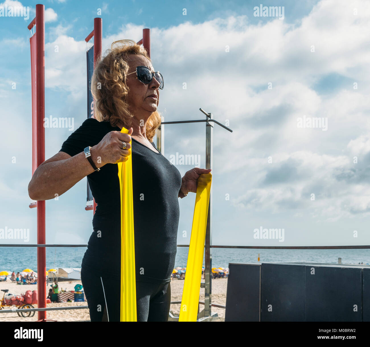 Model Released: Mature woman (70-75) exercising with a stretch cord at open air gym in Ipanema Beach, Rio de Janeiro, Brazil Stock Photo