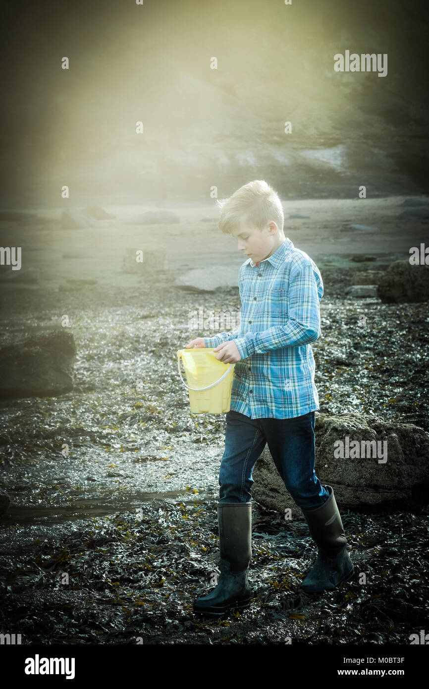 One 12 year old boy walking by the sea, Yorkshire seaside, Runswick Bay, UK. Freedom on holiday. Stock Photo