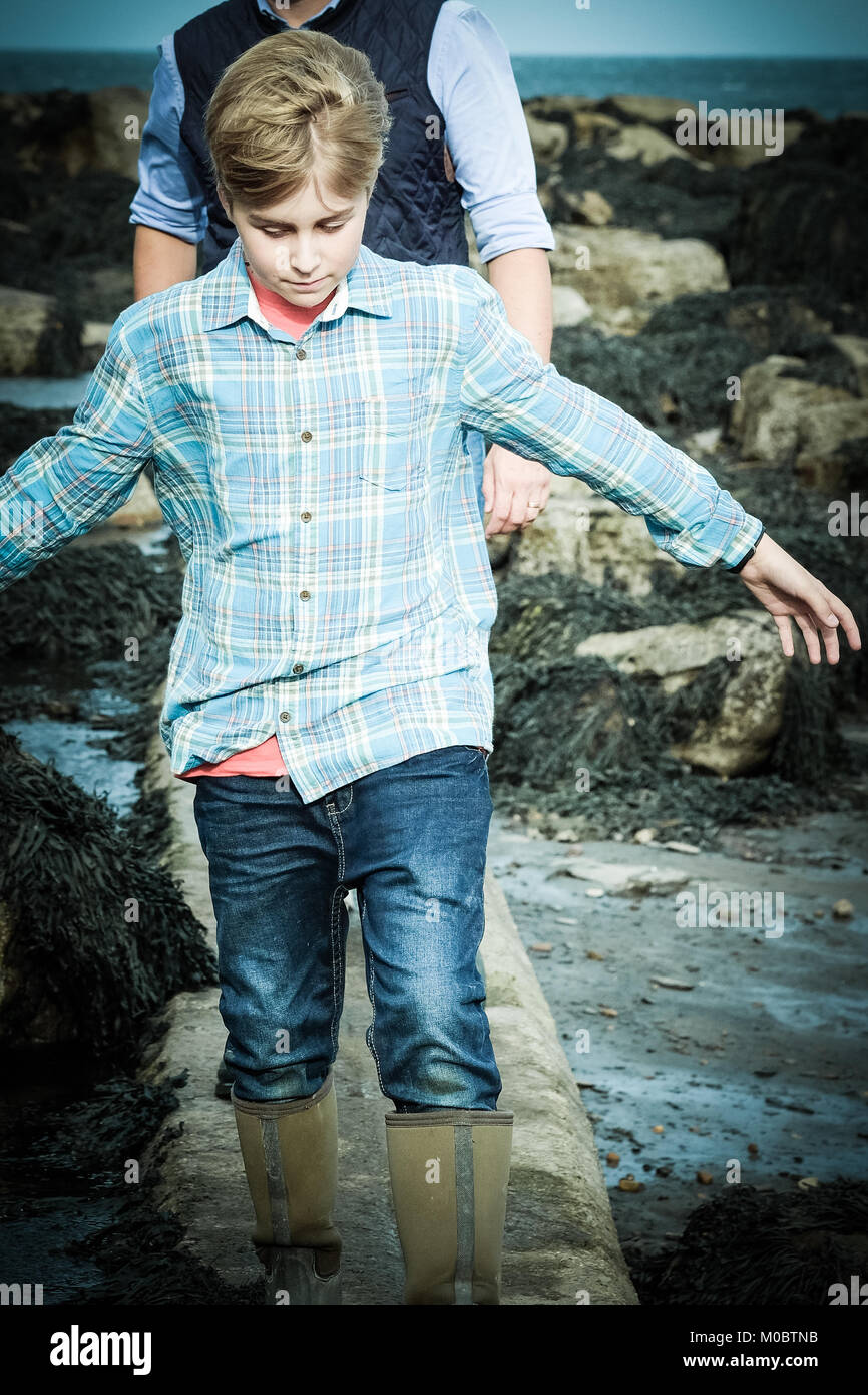 One 12 year old boy walking by the sea, Yorkshire seaside, Runswick Bay, UK. Freedom on holiday. Stock Photo