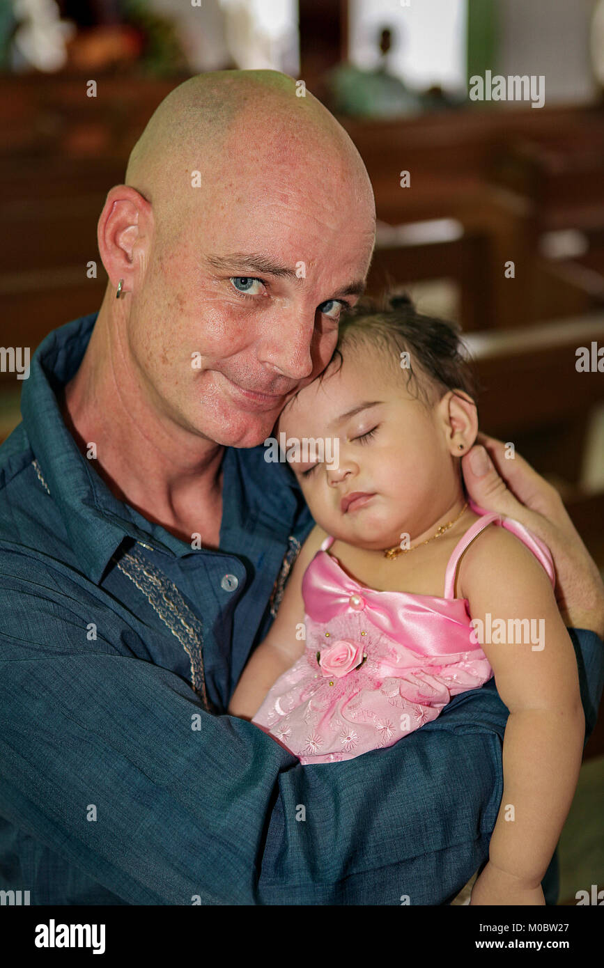 A man tenderly cuddling a young child in his arms with a look of love and pride on his face. Stock Photo