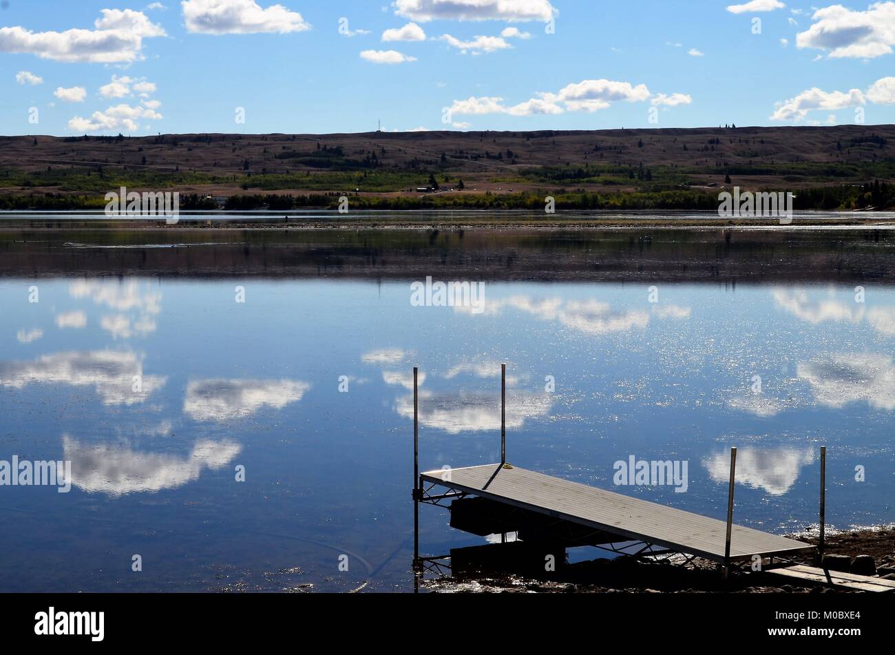 A wonderful water reflection, show white puffy clouds reflecting off of calm waters, at a fishing lake in Montana, USA during the summer months Stock Photo