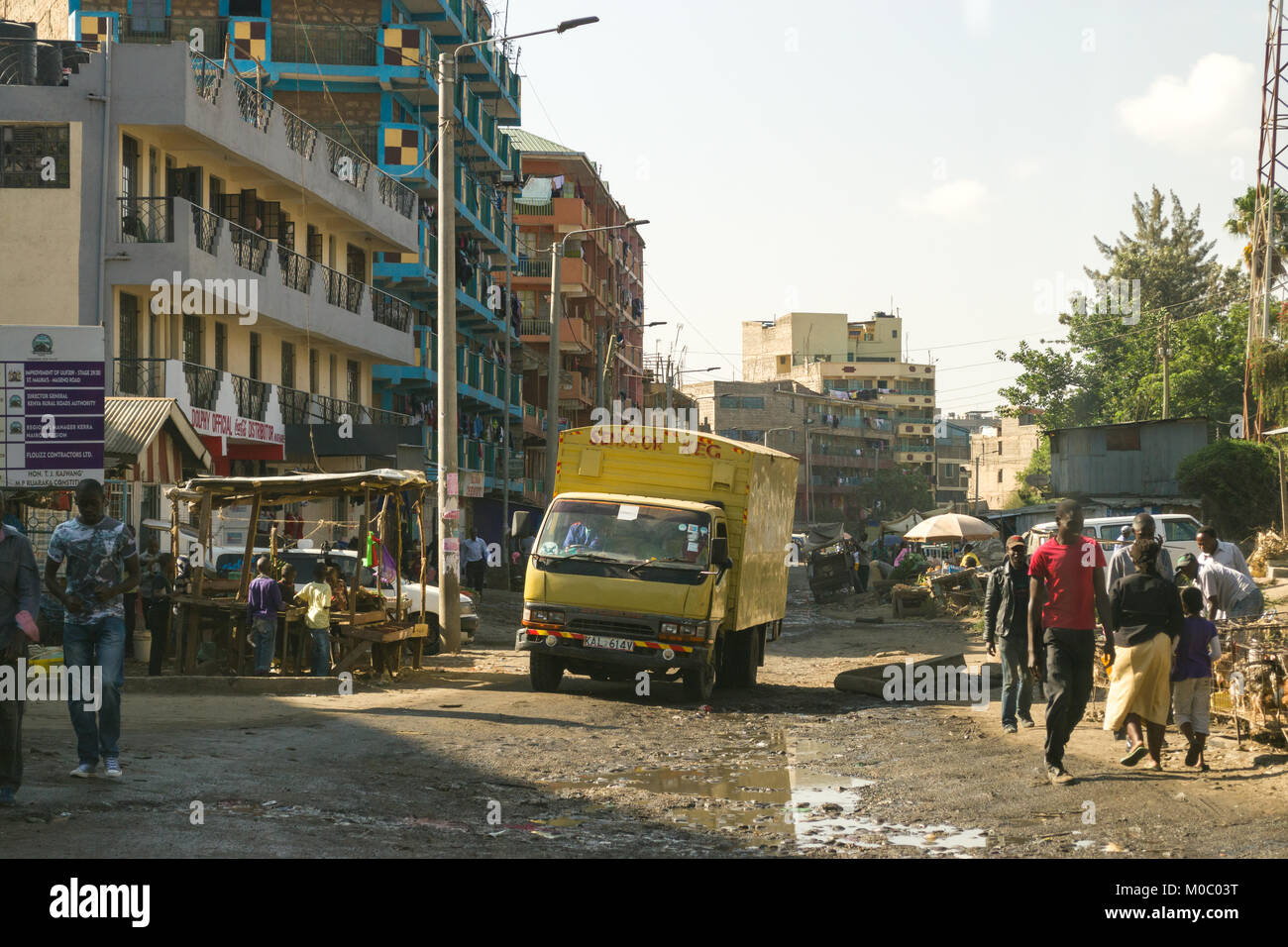 View down a road in Huruma, a district of Nairobi, showing a truck driving down the muddy road as well as people and buildings, Nairobi, Kenya, East A Stock Photo