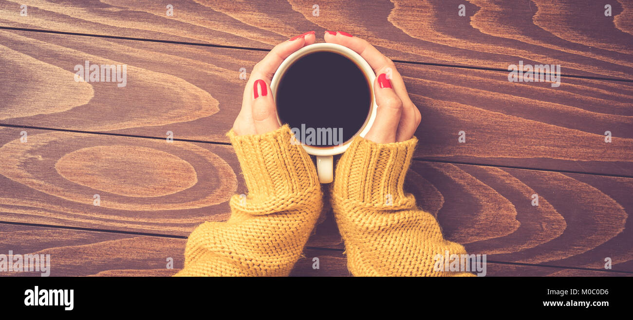 Female hands in warm sweater holding cup of coffee. Top view Stock ...