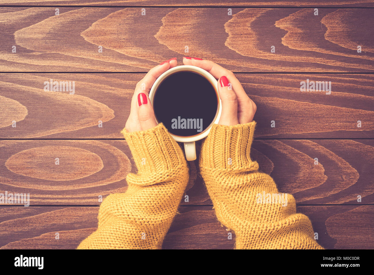 Female hands in warm sweater holding cup of coffee. Top view Stock ...