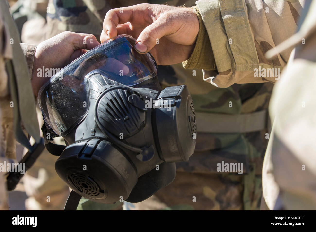 U.S. Marine Corps Sgt. Johnathon Rhodes, right, a Chemical, Biological, Radioactive and Nuclear defense specialist, with 1st Tank Battalion, 1st Marine Division, demonstrates how to utilize the M50 Joint Service General Purpose Mask Delta Company during exercise Steel Knight 2018 at Marine Corps Air Ground Combat Center, Twentynine Palms, Calif., Dec. 7, 2017. Exercise Steel Knight is a 1st Marine Division exercise conducted to successfully demonstrate the capability to exercise command and control over forces in a distributed environment with long range movement, while conducting offensive an Stock Photo