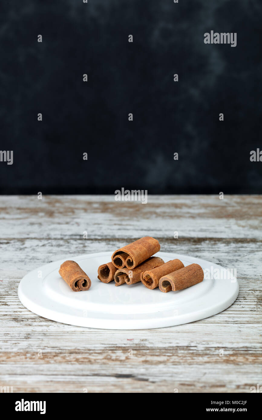 Cassia cinnamon sticks on a old wooden table. Grey and not uniform background with free space for text Stock Photo