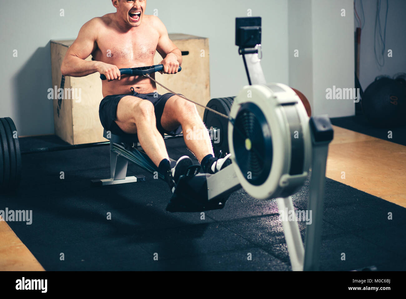 Fit man training on row machine in gym Stock Photo
