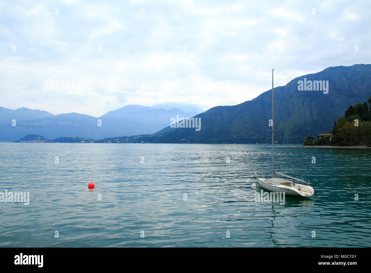 Einsames Segelboot mit einer roten Boje am Comer See in Italien, bei Lenno Stock Photo