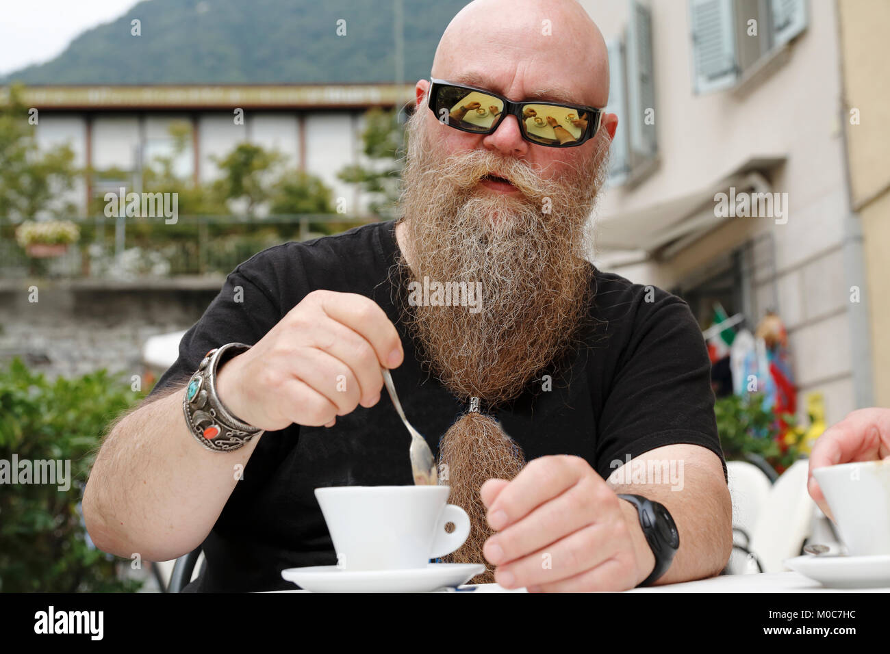 Mann mit langem Bart und Sonnenbrille, genießt eine Tasse Kaffee, Cappuccino Stock Photo