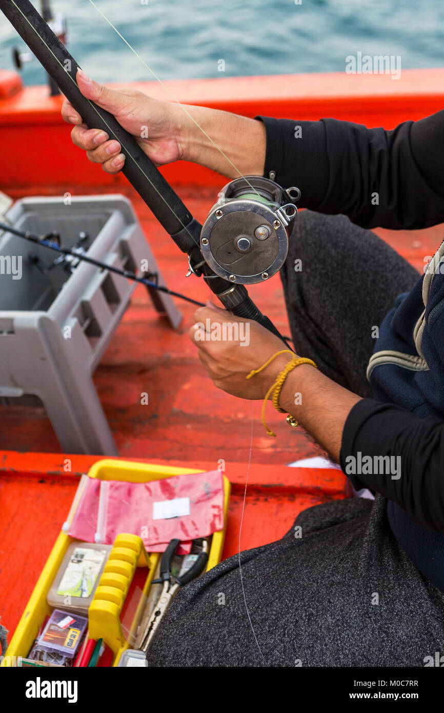 asian man holding a fishing rod with fishing tool box on the