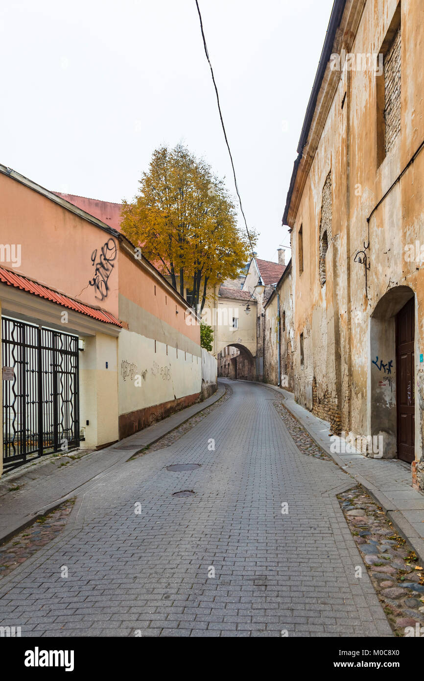 Street view, the narrow Sv Kazimiero Gatve with old dilapidated arch built over the road in the Old Town of Vilnius, capital city of Lithuania Stock Photo