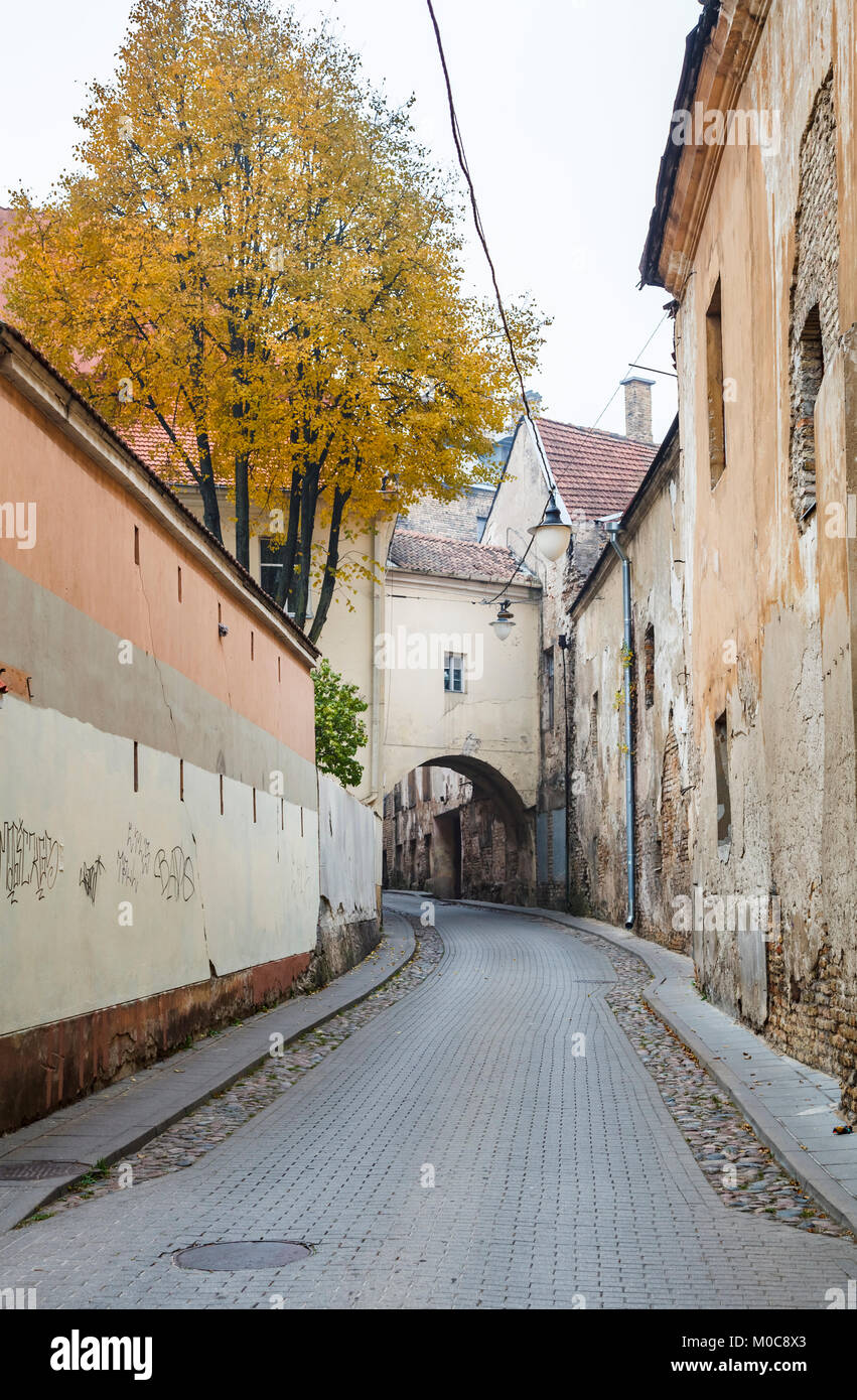 Street view, the narrow Sv Kazimiero Gatve with old dilapidated arch built over the road in the Old Town of Vilnius, capital city of Lithuania Stock Photo