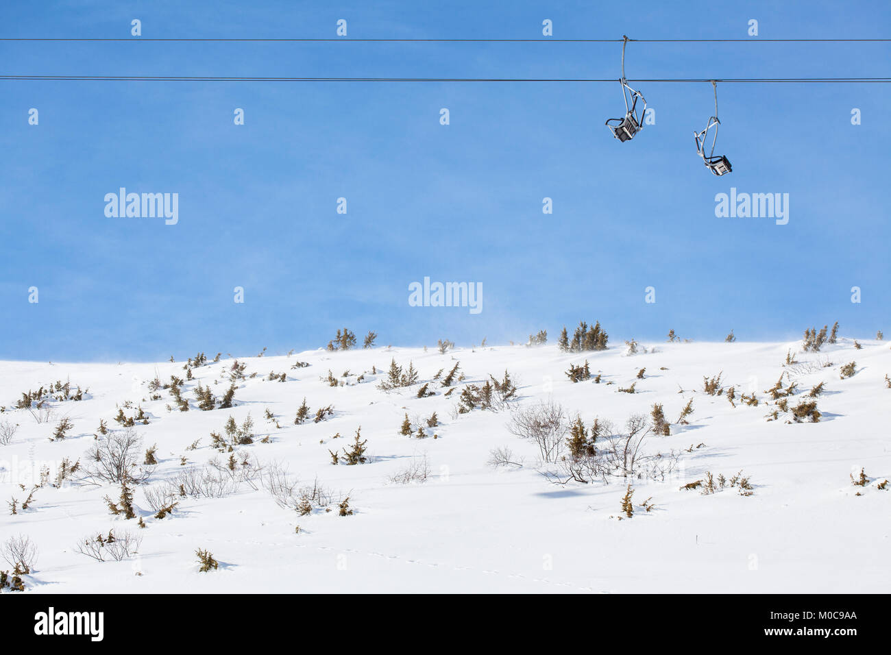 ski chair lift with two double seats, against blue sky, above snowy ...