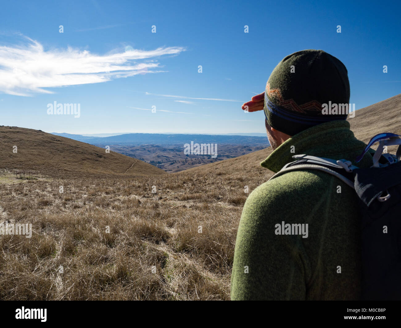 Adult man gazing into distance with eyes shielded toward sunny golden, grassy rolling hills in Morgan Territory Regional Preserve, California, fall Stock Photo