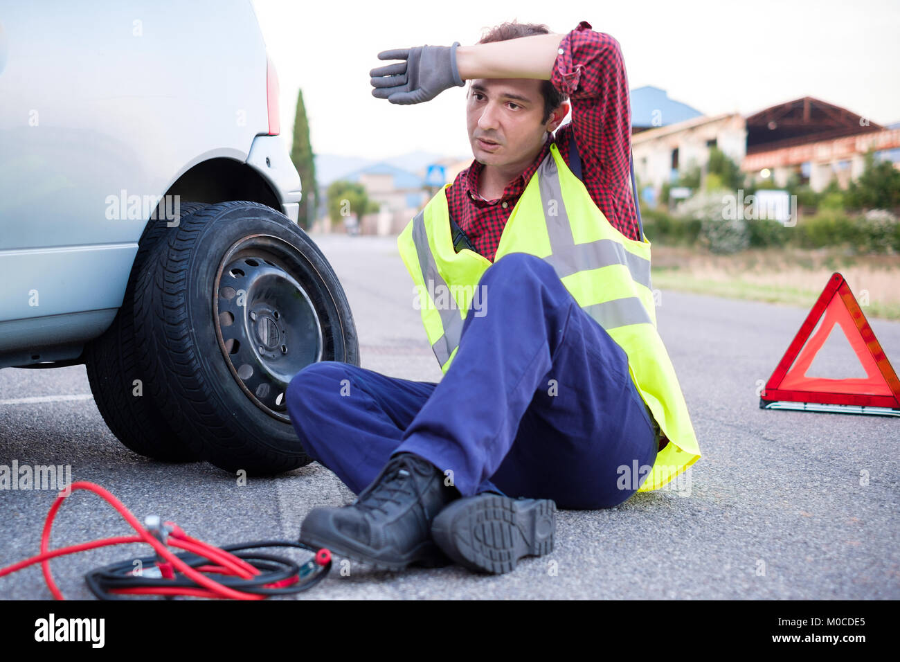 Man changing a flat tire on the side of the road Stock Photo - Alamy