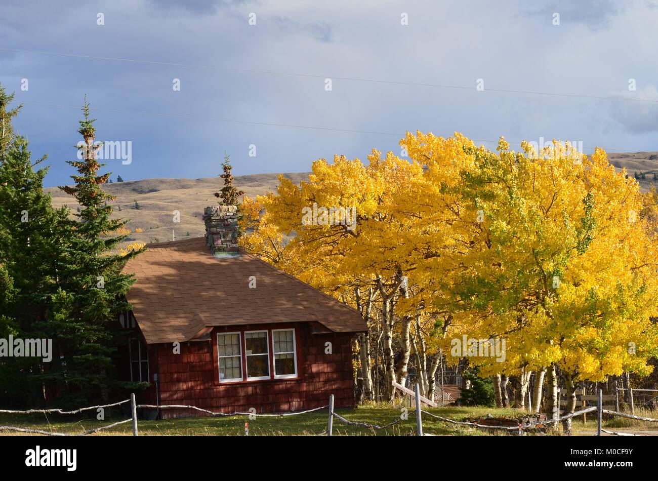 An old historic mountain cabin, sits nestled among the autumn colored trees Stock Photo