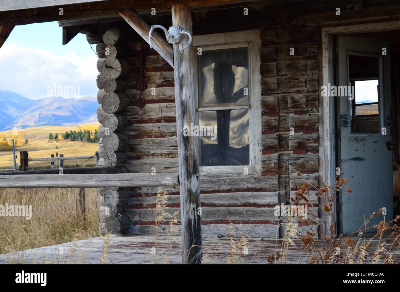 Here sits an old abandoned log cabin, in the middle of a field with a wonderful porch view of the mountains and the rolling hills Stock Photo