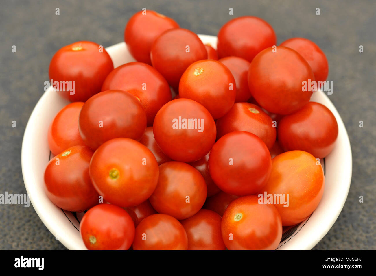 Freshly picked bowl of ripe Cherry tomatoes, variety F1 Sweet Million. Stock Photo