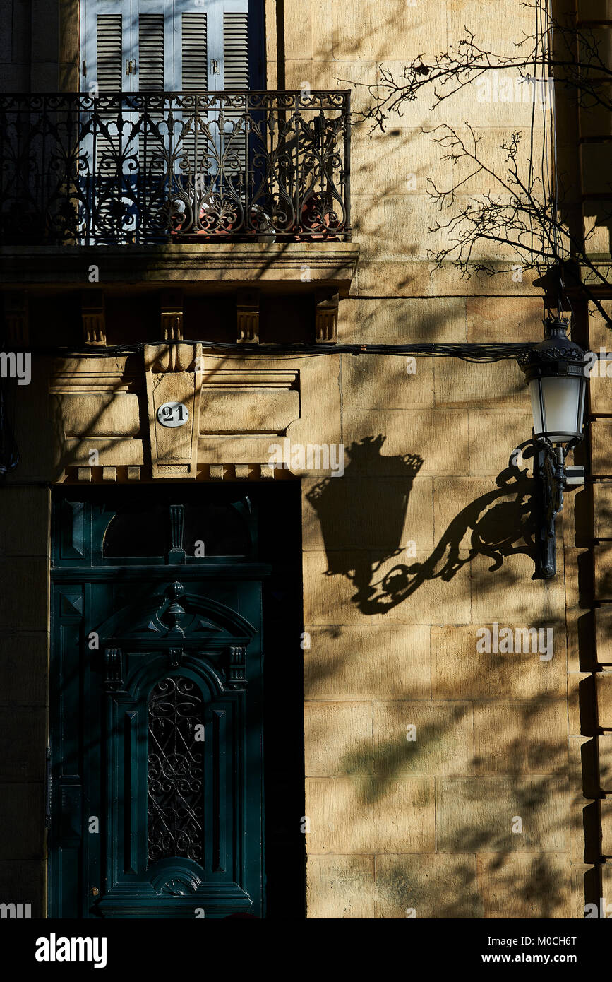 Antique wooden door at sunset with a streetlight shadow over a wall on a European street. Stock Photo