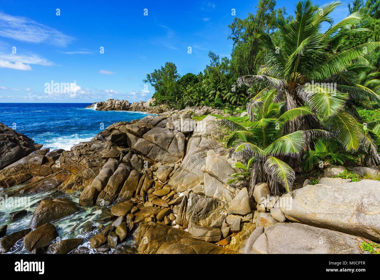 Beautiful and wild lonely beach with rough granite rocks, white