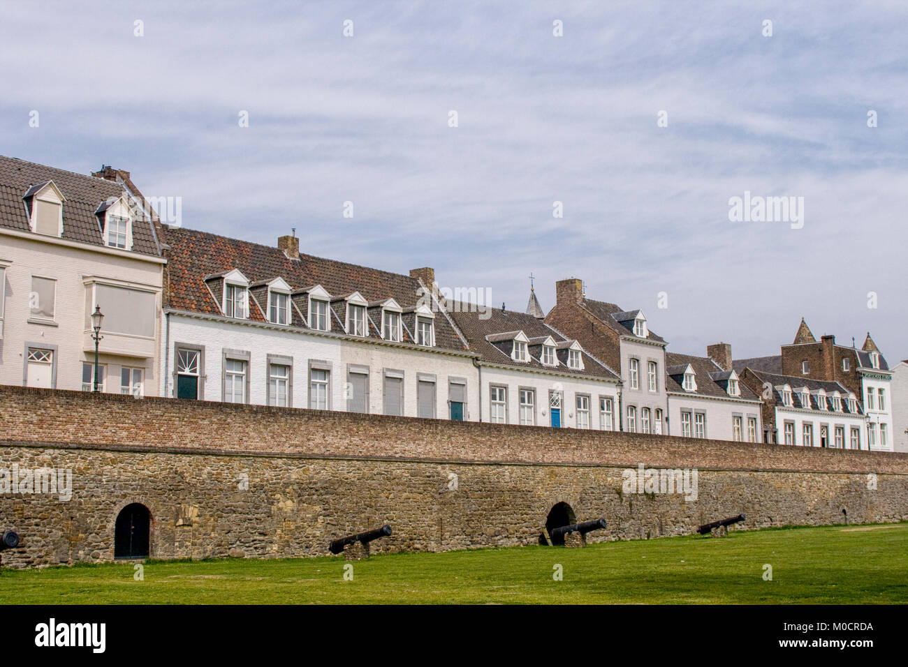 Houses behind a medieval city wall with canons used to defend the city of Maastricht in the Netherlands Stock Photo