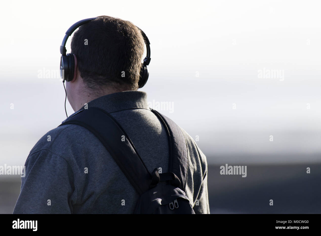 Man wearing wired headphones looking away from camera. Stock Photo
