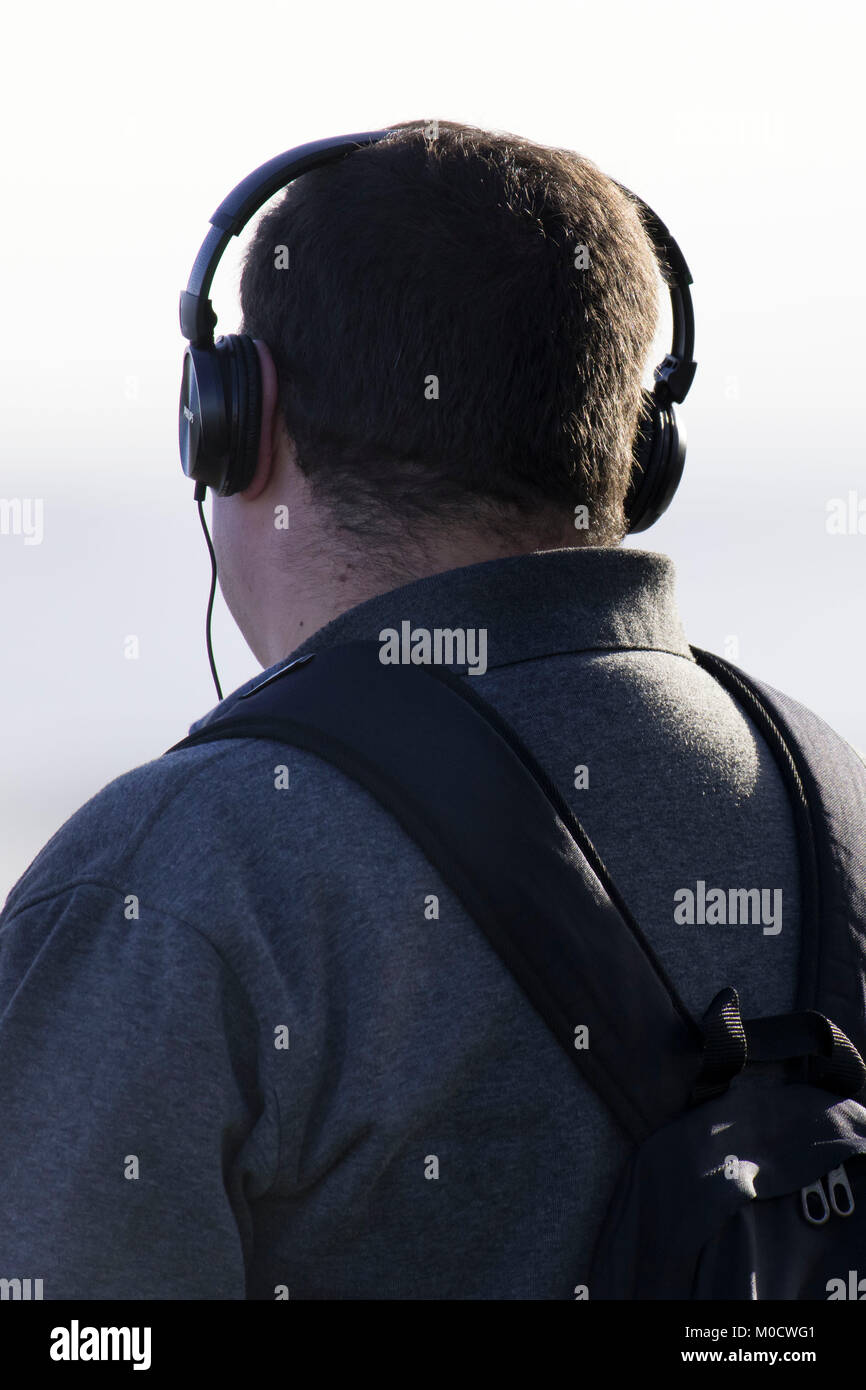 Man wearing wired headphones looking away from camera. Stock Photo