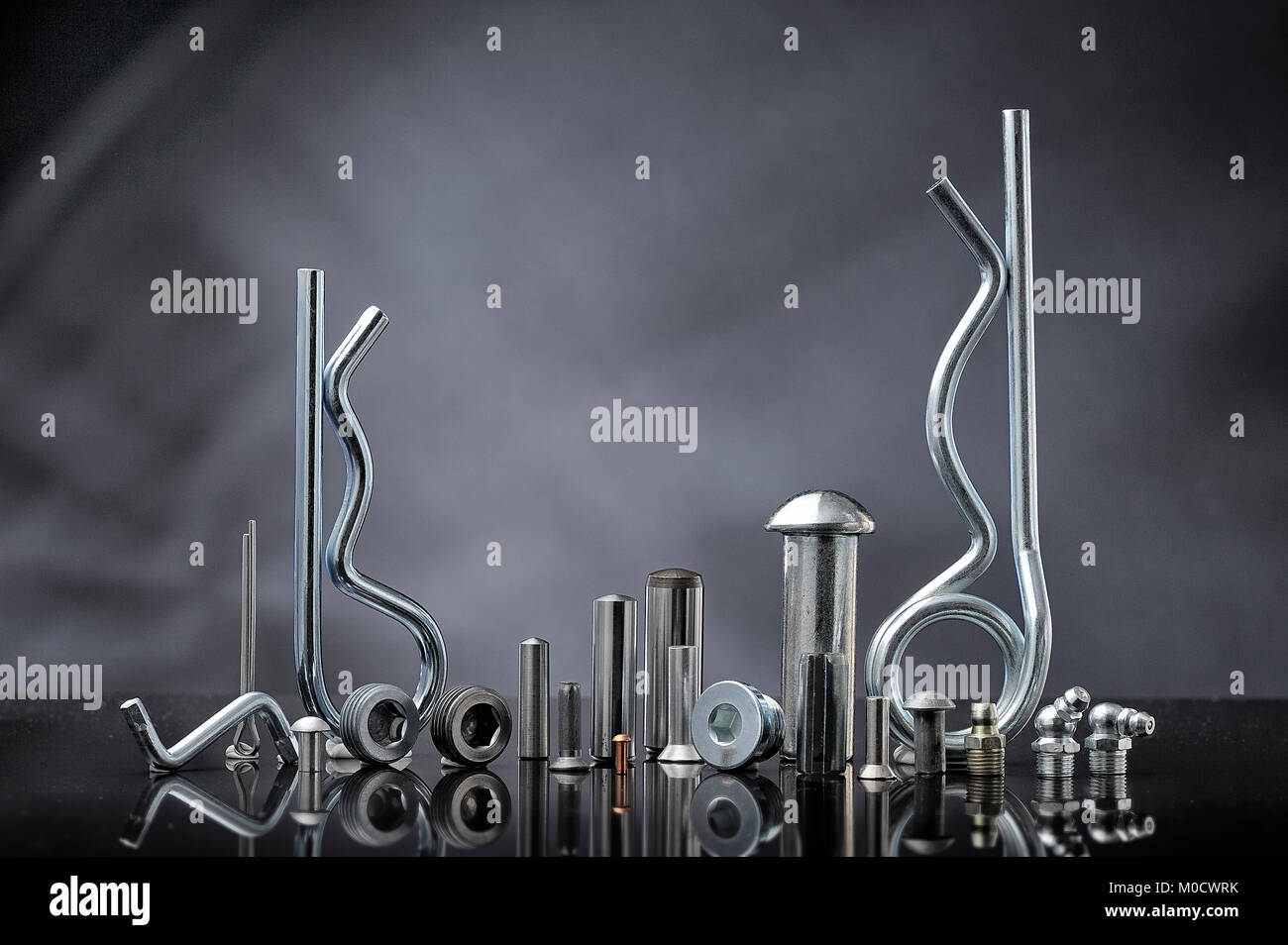 Mounting hardware made of metal. Many types of metal pins on gray background Stock Photo