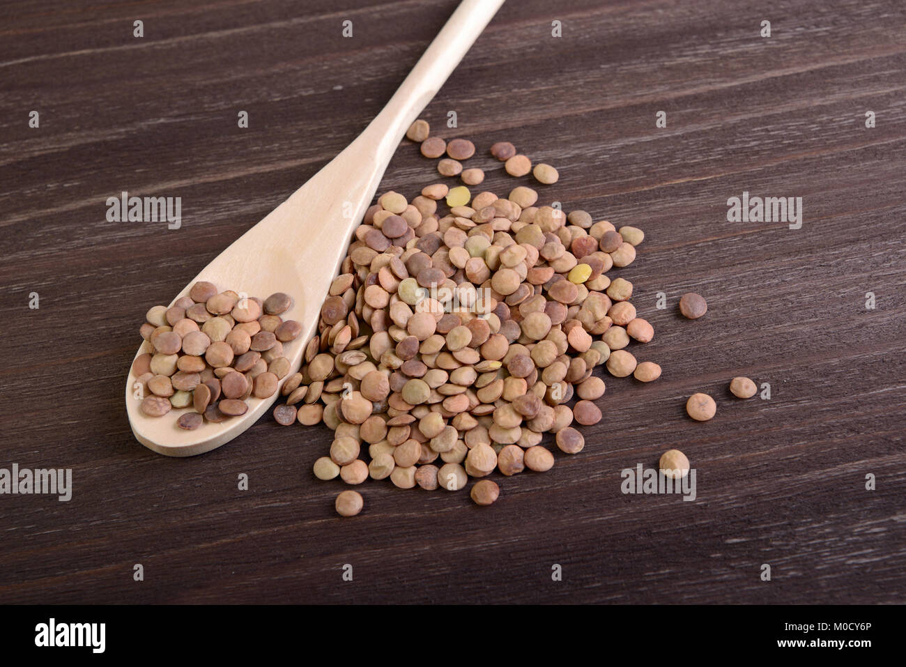Handful of lentils and spoon on a wooden background Stock Photo