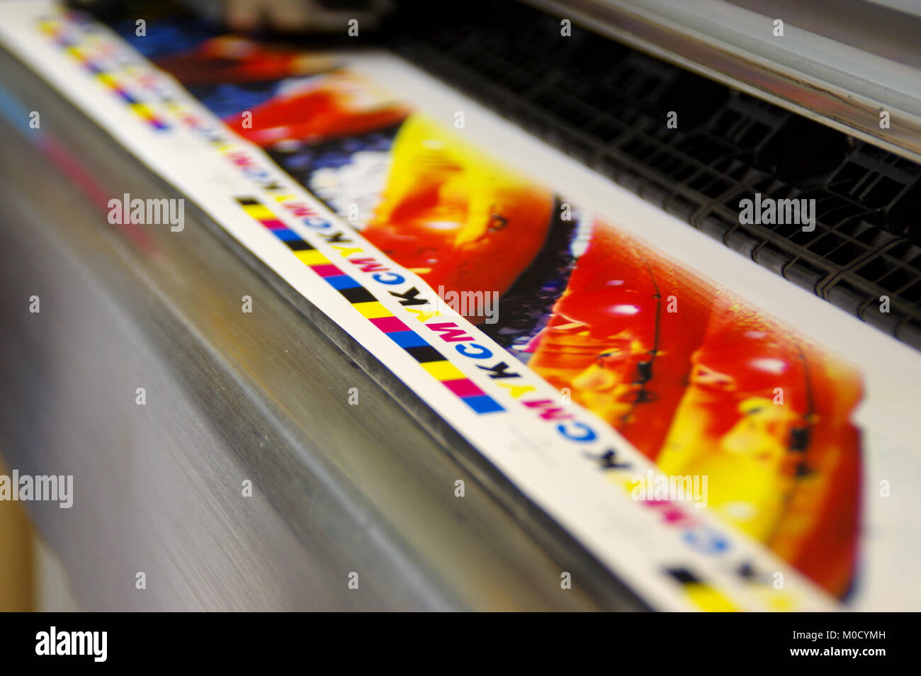 Inkjet plotter printing CMYK mark on white paper. Large digital printer machine. Stock Photo