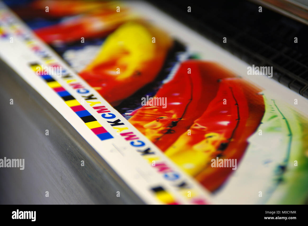 Inkjet plotter printing CMYK mark on white paper. Large digital printer machine. Stock Photo