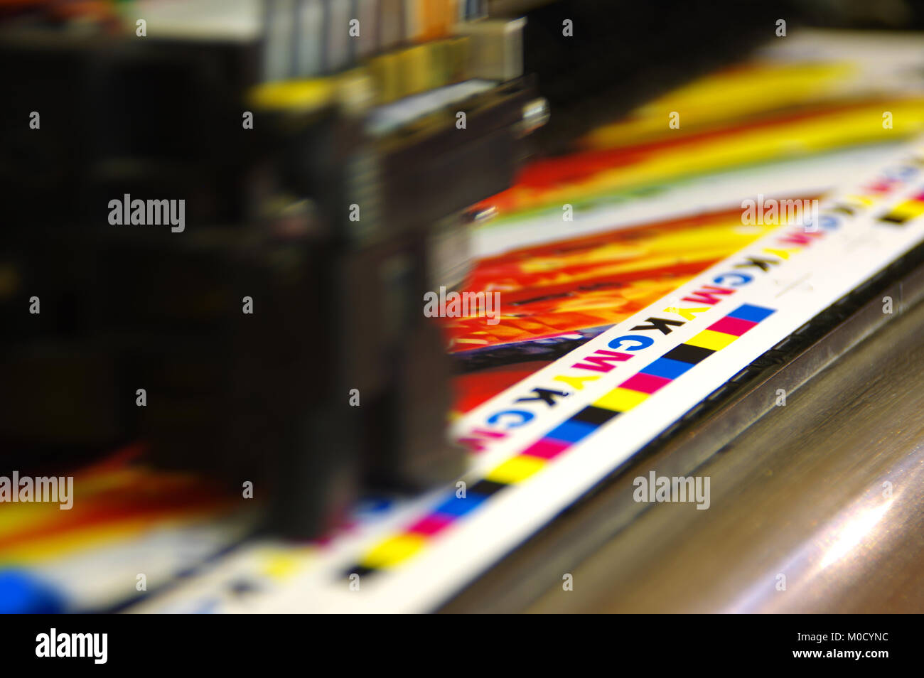 Printing head creates CMYK test and image on paper. Colorful large plotter printer machine. Stock Photo