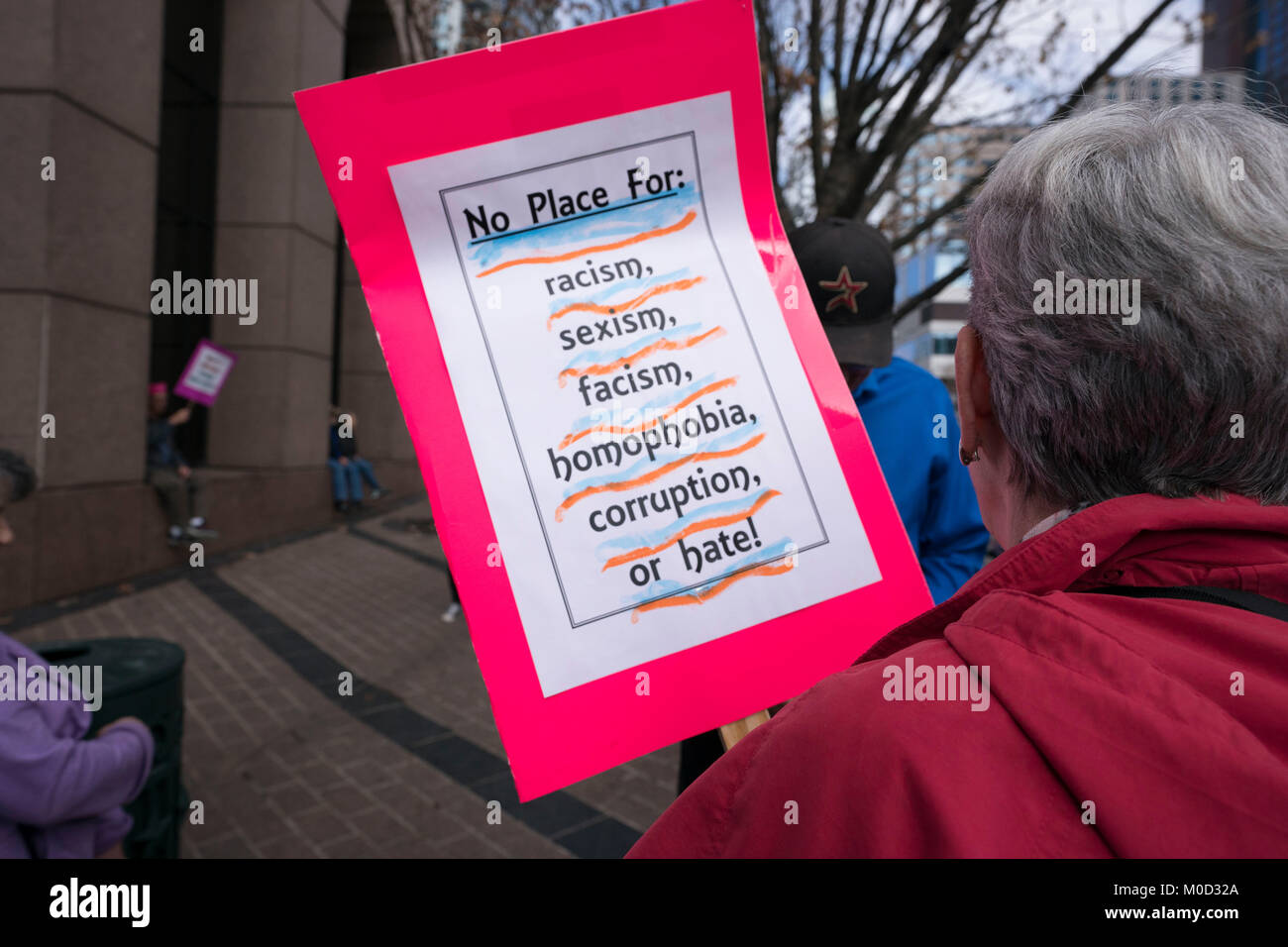 A woman holds a sign protesting racism, sexism, fascism, homophobia, corruption and hate as Texas women march up Congress Avenue in Austin, Texas, during a rally on the first anniversary of the Women's March on Washington and a year after President Donald Trump's inauguration. Stock Photo