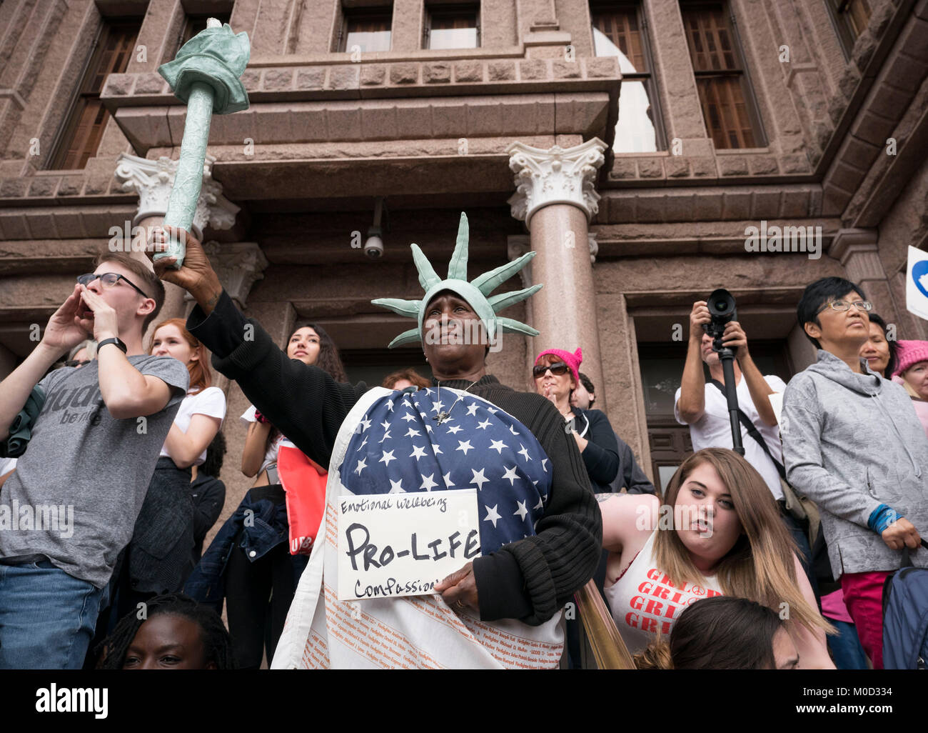 Peace Costanzo, a daily visitor to the Texas Capitol in her Statue of Liberty-like costume, stands on the Capitol steps surrounded by protesters  during a women's rights rally commemorating the anniversary of last year's Women's March on Washington and Pres. Donald Trump's controversial first year in office. Stock Photo