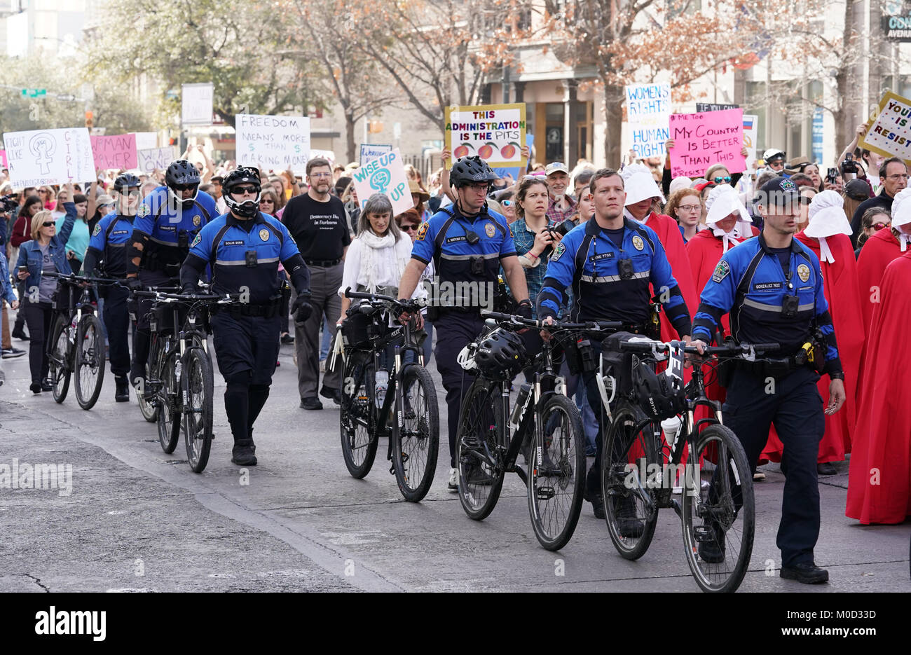 Police on bicycles patrol alongside women and men marching up Congress Avenue to the Texas Capitol in Austin for a rally on the first anniversary of the Women's March on Washington and a year after President Donald Trump's inauguration. Stock Photo