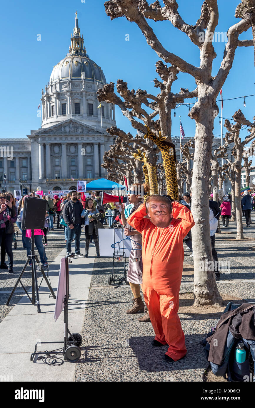 San Francisco, California, USA. 20th January, 2018. The 2018 Women's March in San Francisco, organized by Women's March Bay Area. A demonstrator wears a Donald Trump mask with an orange prison jump suit while dancing to music in San Francisco Civic Center during the rally before the women's march. City hall is in the background. Credit: Shelly Rivoli/Alamy Live News Stock Photo