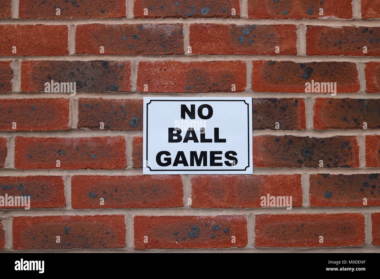 'No Ball Games' sign on red brick wall Stock Photo