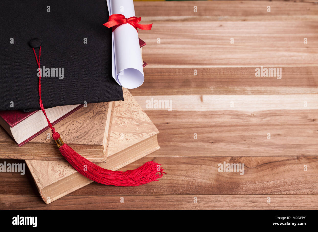 Black graduation cap and diploma on a stack of books Stock Photo - Alamy