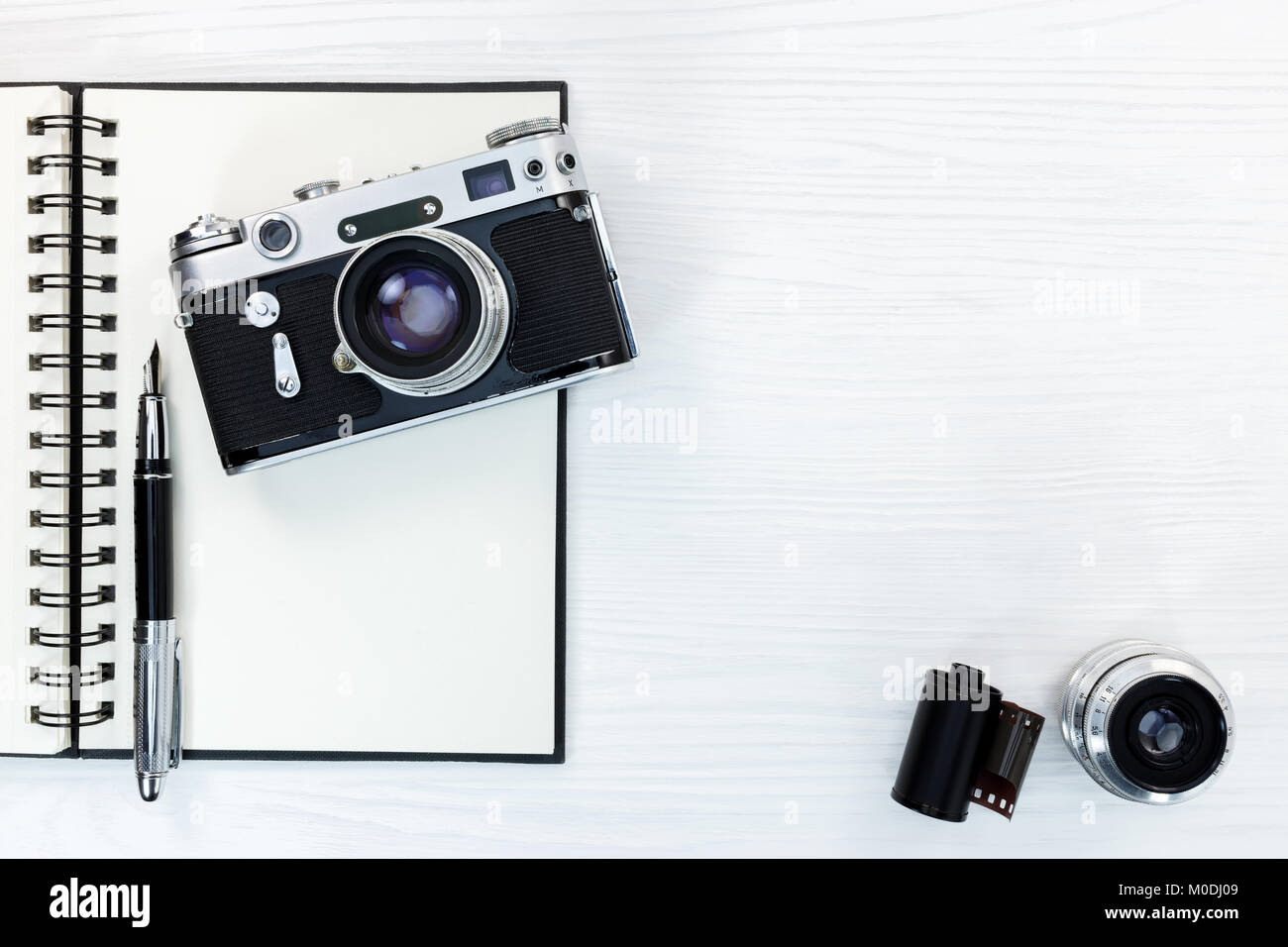 vintage camera, lens, negative film, open notepad with fountain pen on