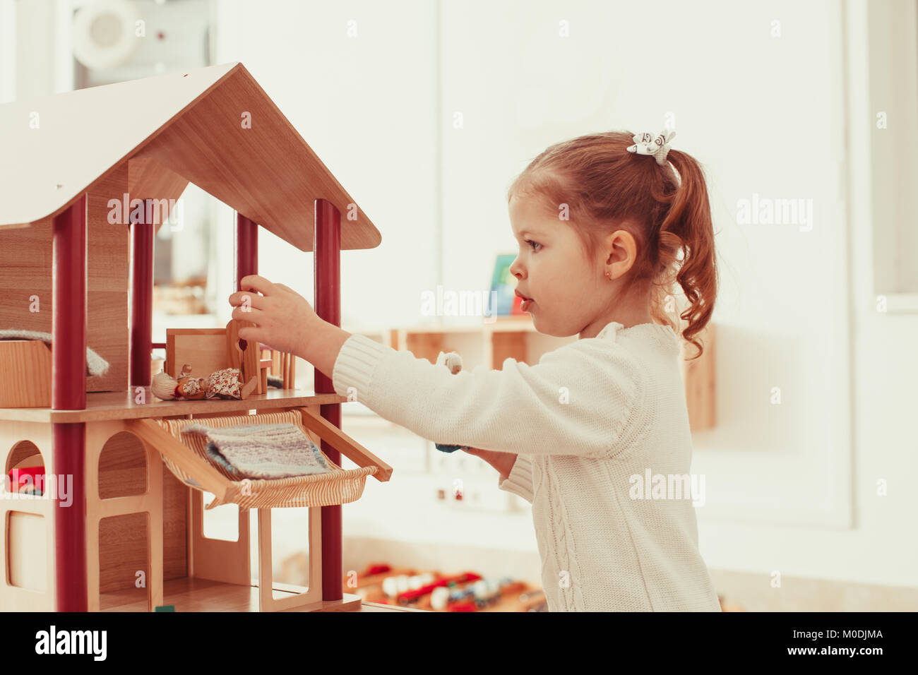 Girl playing with a dollhouse Stock Photo - Alamy