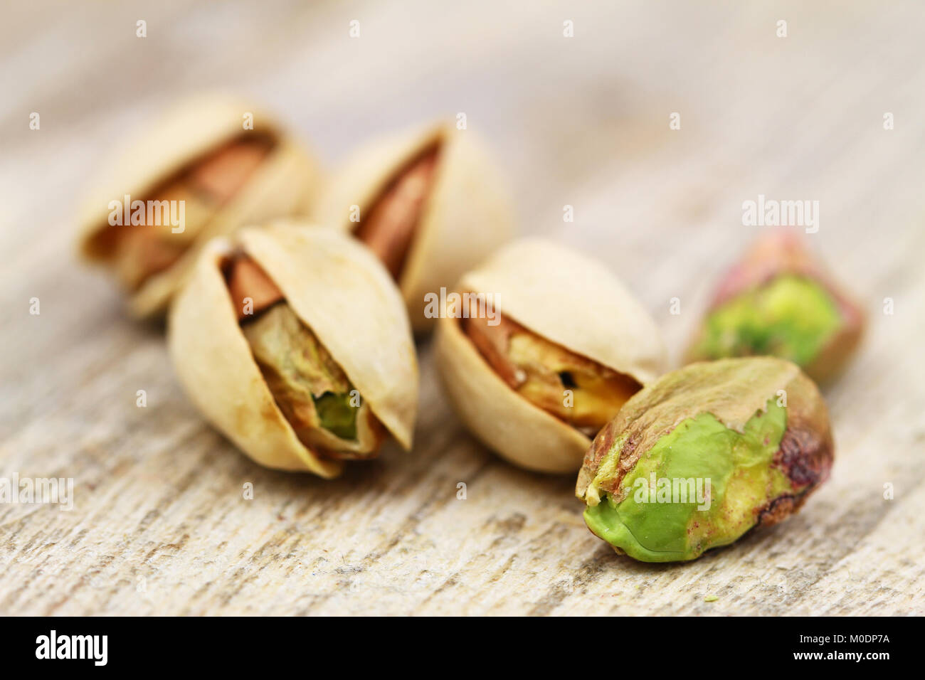 Close up of few pistachio nuts on rustic wooden surface Stock Photo