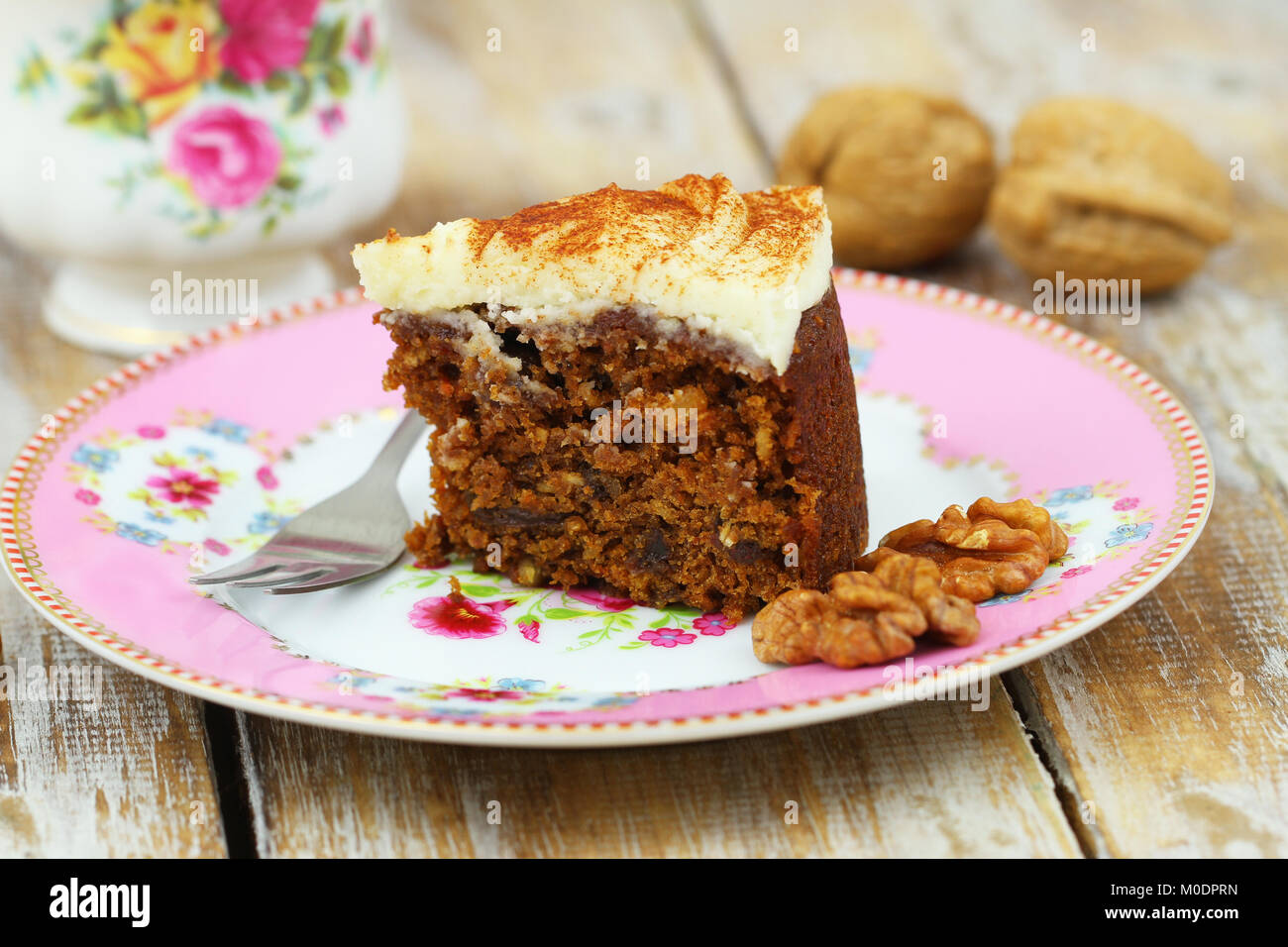 Slice of delicious carrot cake with walnuts with marzipan icing on pink plate Stock Photo