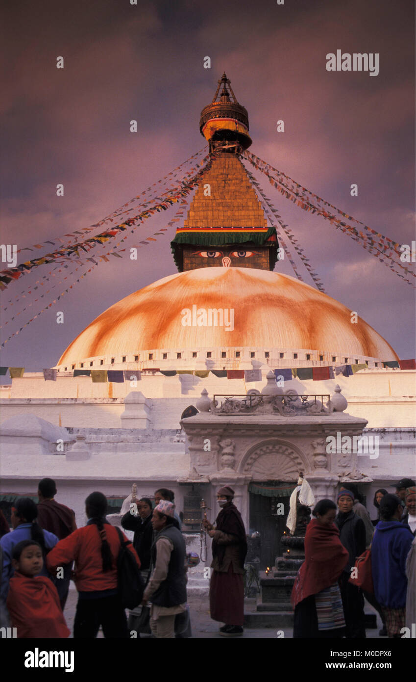 Nepal, Kathmandu. Bodnath temple, stupa (Buddhism). Pilgrims outside temple, dusk. Stock Photo