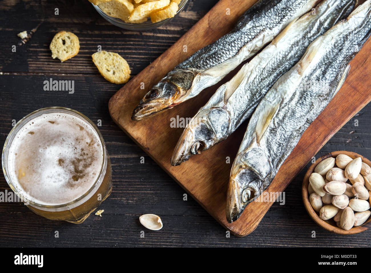 Assorted snacks for beer: sun dried fish, nuts, salted croutons or crackers and over wooden background, top view, copy space. Lager beer and snacks, d Stock Photo