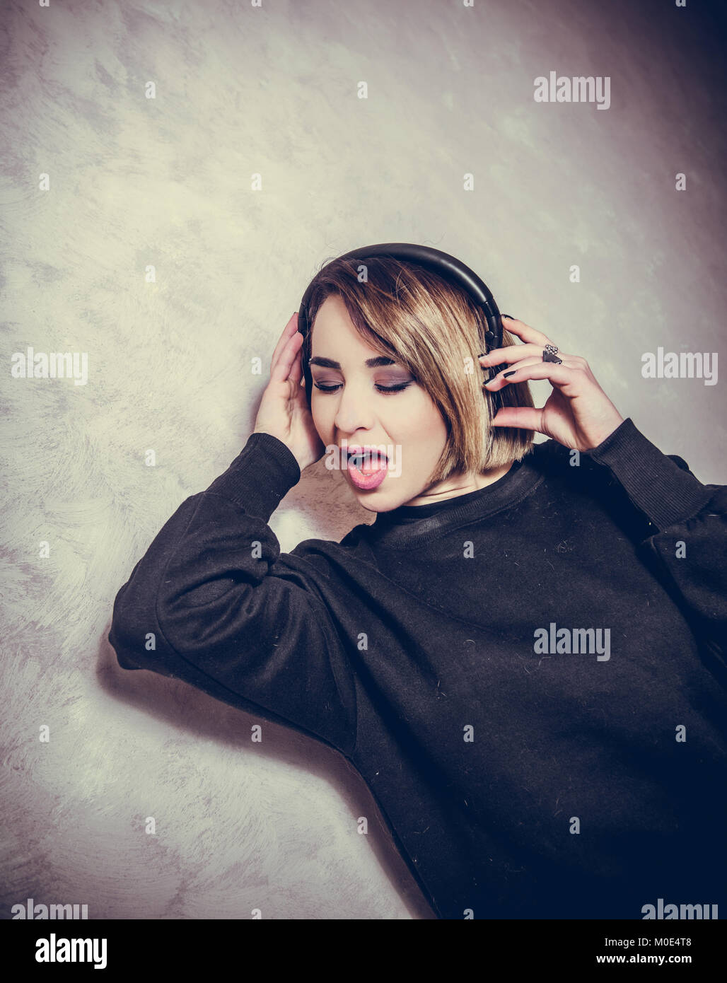 Young beautiful blond girl with headphones enjoy herself listening music with closed eyes and open mouth Stock Photo