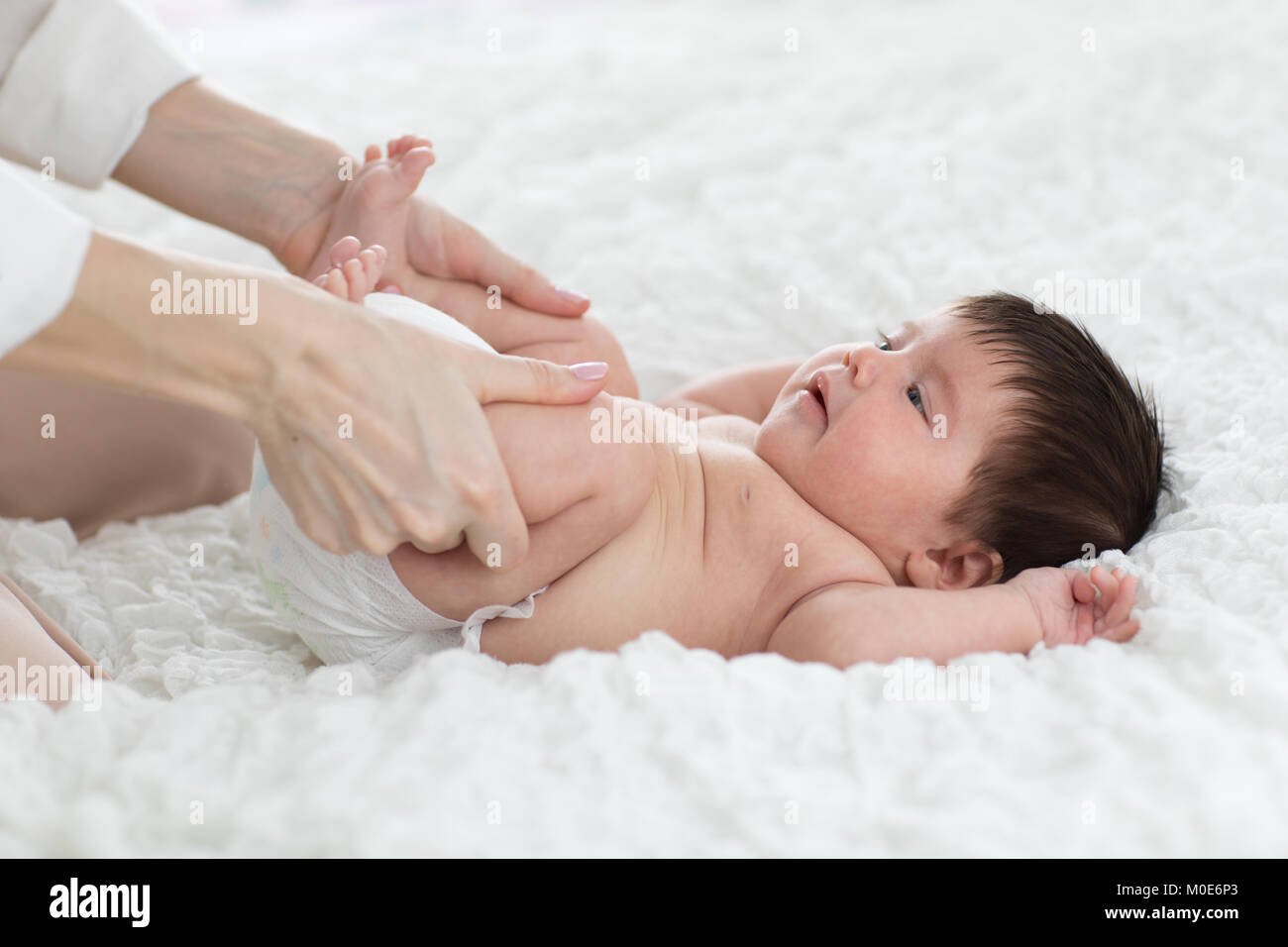 baby newborn is enjoying massage from mother Stock Photo