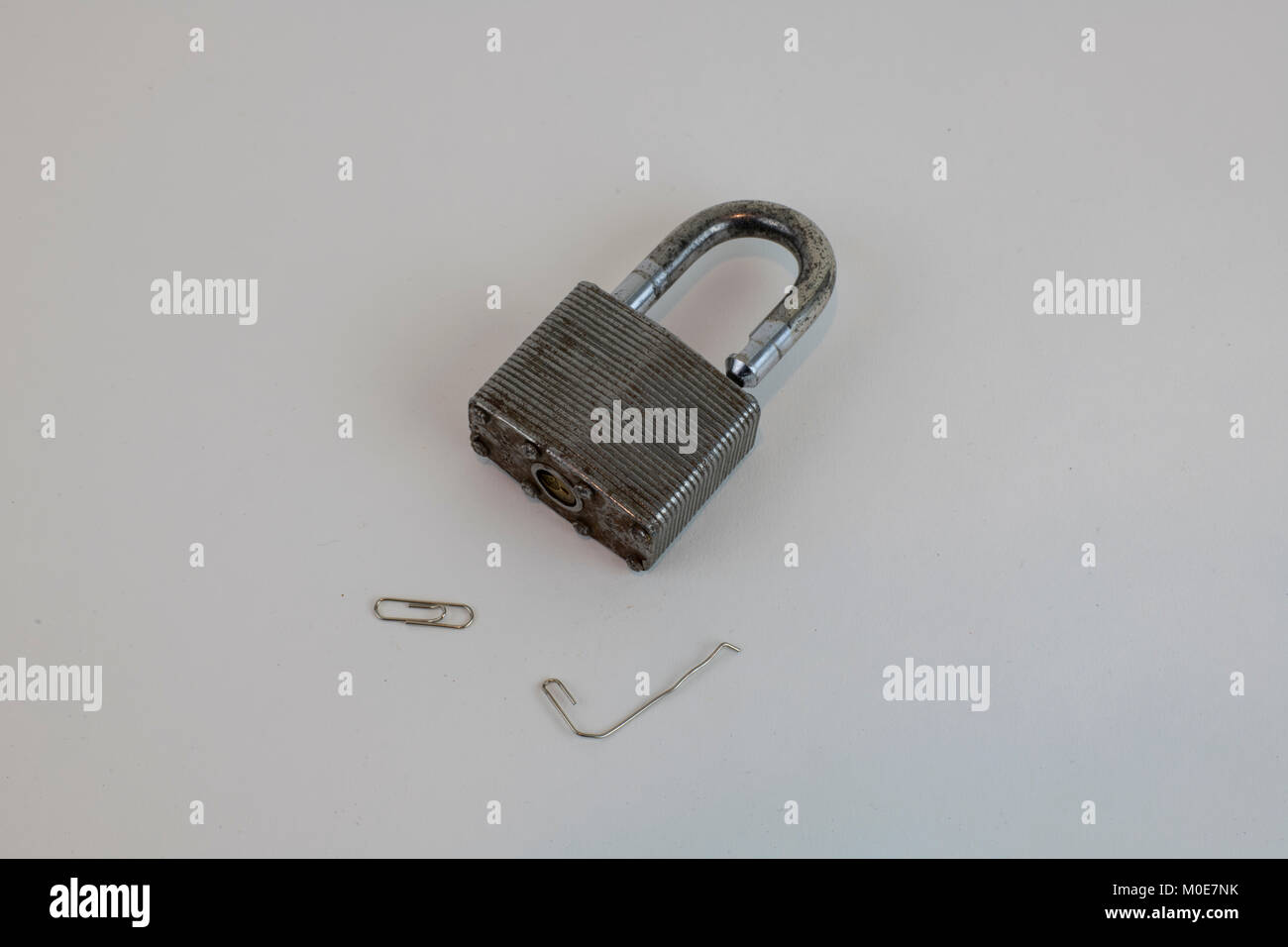 Padlock opened with paper clip against white background to illustrate