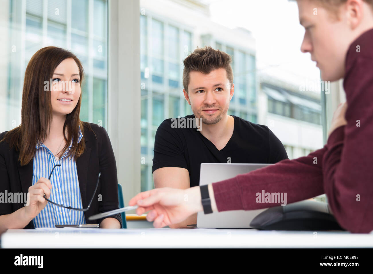 Business People Looking At Colleague Explaining At Desk Stock Photo